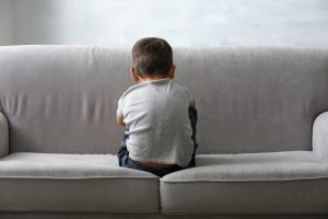 Little boy sits backwards on sofa looking away from the camera | children and anxiety | anxiety treatment | child counseling and play therapy | 30076