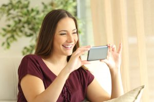 happy woman uses her phone for online therapy in Georgia with Wellview Counseling