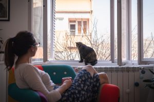 woman looks at her cat in the window of her home. She gets online therapy in georgia with wellview counseling