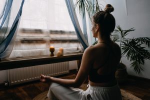 women meditates near a window representing how some individuals choose to cope with symptoms of Trauma and PTSD