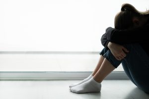 young woman in the shadows hugs her knees after experiencing complex trauma or C-PTSD. She gets trauma treatment in Roswell, GA and Atlanta, GA at Wellview Counseling