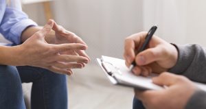A therapist writes on their clipboard as the client gestures. This could represent anxiety treatment in Roswell, GA with an anxiety therapist. Contact one today to learn about anxiety counseling today.