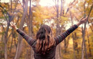 A woman extends her hands as she stands in a forest. This could represent the graditute that online therapy in Atlanta, GA can cultivate. Contact a therapist in Roswell, GA to learn more about DBT therapy in Roswell, GA and other services! 30076