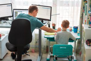 A father sitting at a computer desk helps his child with an activity next to them. A child therapist in Roswell, GA can help you and your child overcome mental health concerns. Learn more about child counseling in Roswell, GA by contacting Wellview Counseling today! 30076