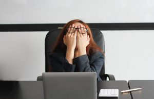 A student covers their face while sitting in front of a laptop. This could represent the burnout a young adult therapist in Roswell, GA can address. Learn more about young adult therapy in Roswell, GA by contacting a therapist in Roswell, GA today! 30076