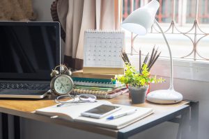 A laptop rests on a table with work supplies and a clock for Wellview Counseling. Learn more about life transitions therapy in Roswell, GA can offer support with individual counseling in Roswell, GA and other services. 30076