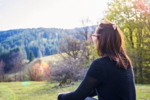 Photo of a woman sitting in a field. This photo represents the way deep breathing and grounding techniques can help you cope with physical symptoms of anxiety. Our counselors offer online anxiety counseling in Georgia to help you manage your anxiety.