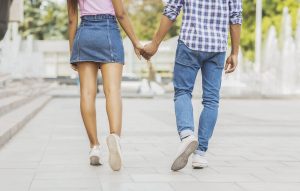 Photo of two young people walking hand in hand representing a relationship where the couple communicates effectively and one person may have used DEARMAN to set boundaries and express their needs.