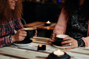 Shows two women talking over coffee. Symbolizes how a life transitions therapist in roswell, ga can help young adults take small steps into forming relationships.